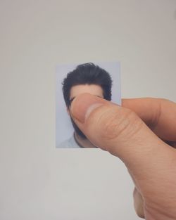 Cropped image of person holding photograph against white wall