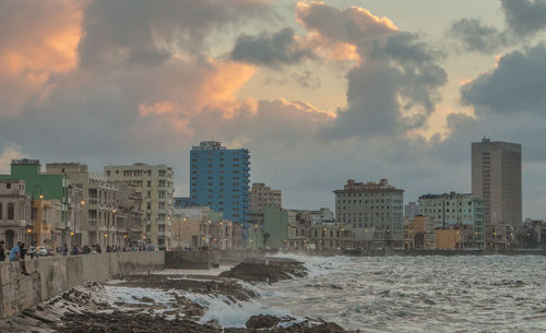 Sea by city against sky during sunset