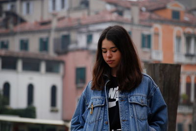 Beautiful young woman standing against buildings in city