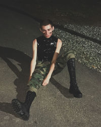 High angle portrait of young man sitting on road