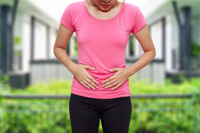 Midsection of woman with pink hair standing against blurred background