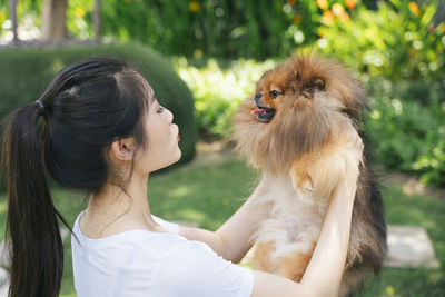 Young woman holding dog standing at park