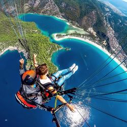Low angle view of men paragliding over sea
