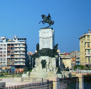 Statue in city against clear blue sky