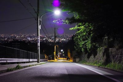 Night view of empty road and lights with city in background