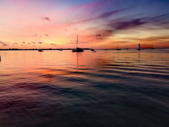 Silhouette sailboats in sea against sky during sunset