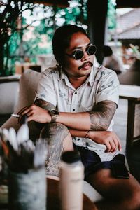 Young man wearing sunglasses sitting outdoors