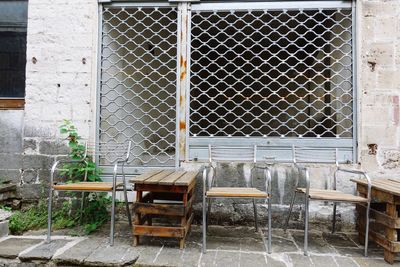 Empty chairs and table against building