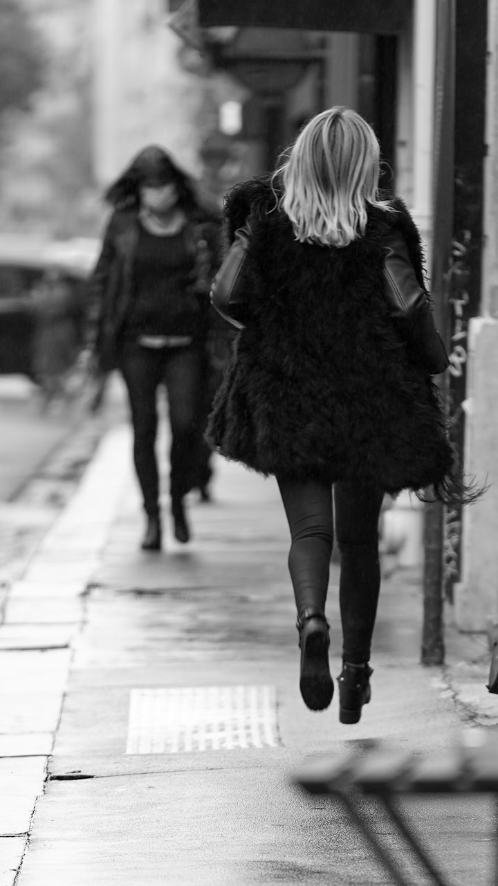 FULL LENGTH REAR VIEW OF WOMAN WALKING ON FOOTPATH