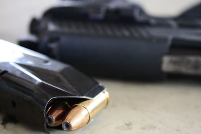 Close-up of magazine with bullets by gun on table