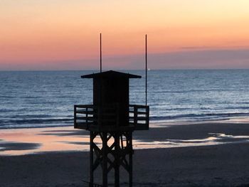 Lifeguard hut on beach against sky during sunset