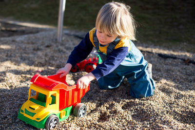 Side view of boy playing with sand at beach