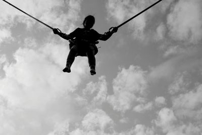 Low angle view of girl jumping against sky