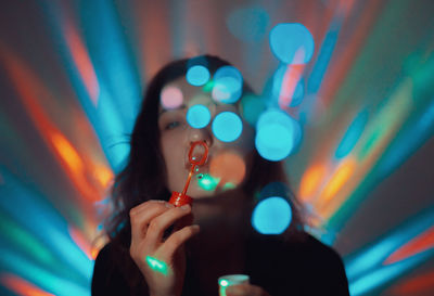 Woman blowing bubbles against illuminated lights