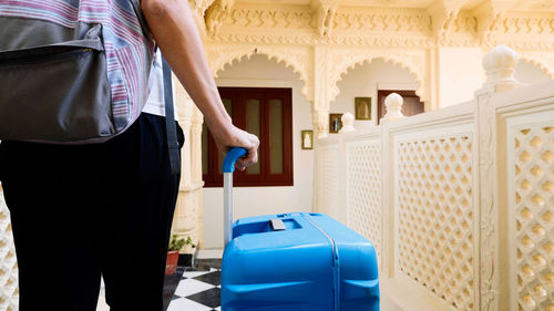 Midsection of woman carrying suitcase at hotel