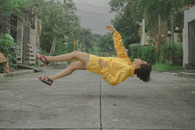 Side view of young woman levitating on road