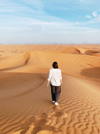 Rear view of man walking at desert