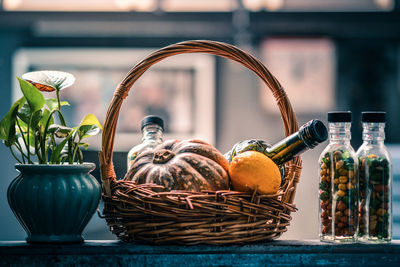 Close-up of food with drink in wicker basket by plants on railing
