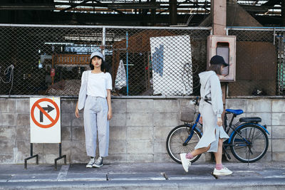 Full length portrait of woman with bicycle standing in city