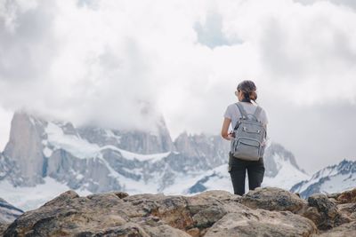 Rear view of woman standing on snowcapped mountain