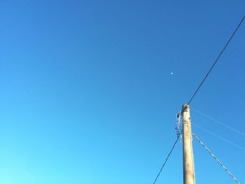 Low angle view of power lines against clear blue sky