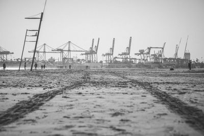 Cranes on pier by sea against clear sky