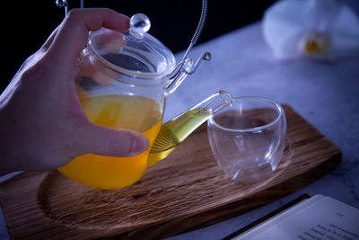 Close-up of person pouring drink in glass on table