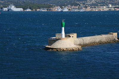 Lighthouse by sea against buildings