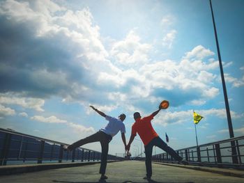 Rear view of people walking on bridge against sky