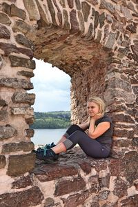 Full length of girl sitting on window