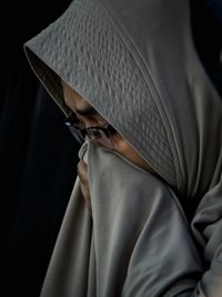 Close-up of mature woman in hijab against black background