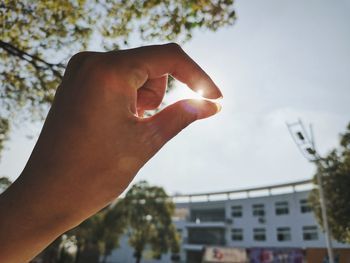 Close-up of person holding hands against sky