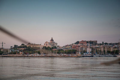 River by buildings in city against clear sky during sunset