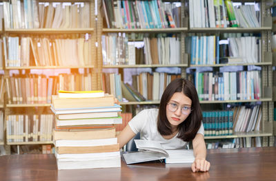 Portrait of young woman studying at desk in library