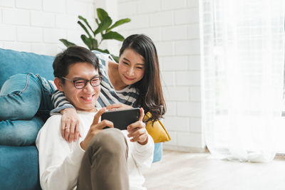 Young woman using mobile phone while sitting on floor