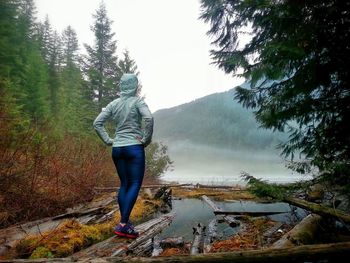 Rear view of man standing by river in forest