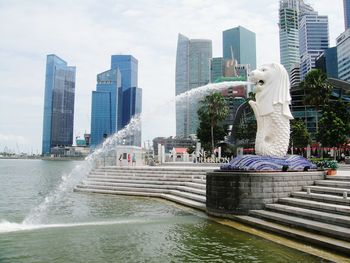 Statue by city against sky