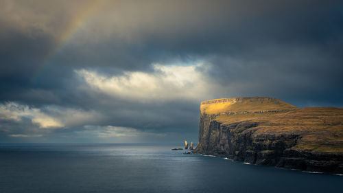 Scenic view of sea and cliff against sky during sunset