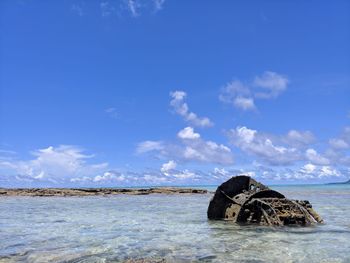 Abandoned boat on beach against blue sky