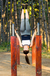 Full length of woman climbing on wooden post in forest
