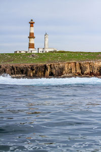 Lighthouse by sea against sky