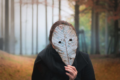 Portrait of person holding autumn leaf outdoors