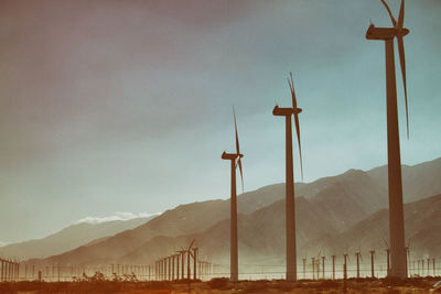 Wind turbines on landscape against clear sky