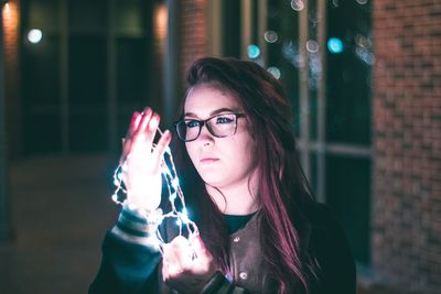 Young woman holding camera at night