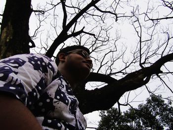 Low angle view of young man looking away against sky