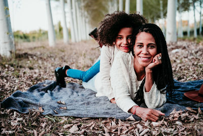 Portrait of smiling daughter lying with mother on land