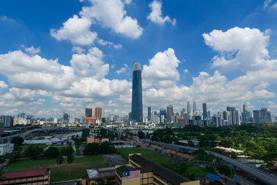 Aerial view of buildings in city against cloudy sky