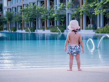 Rear view of girl standing by swimming pool
