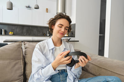 Young woman using mobile phone while sitting on sofa at home