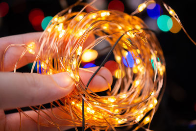 Cropped hand holding illuminated light bulb